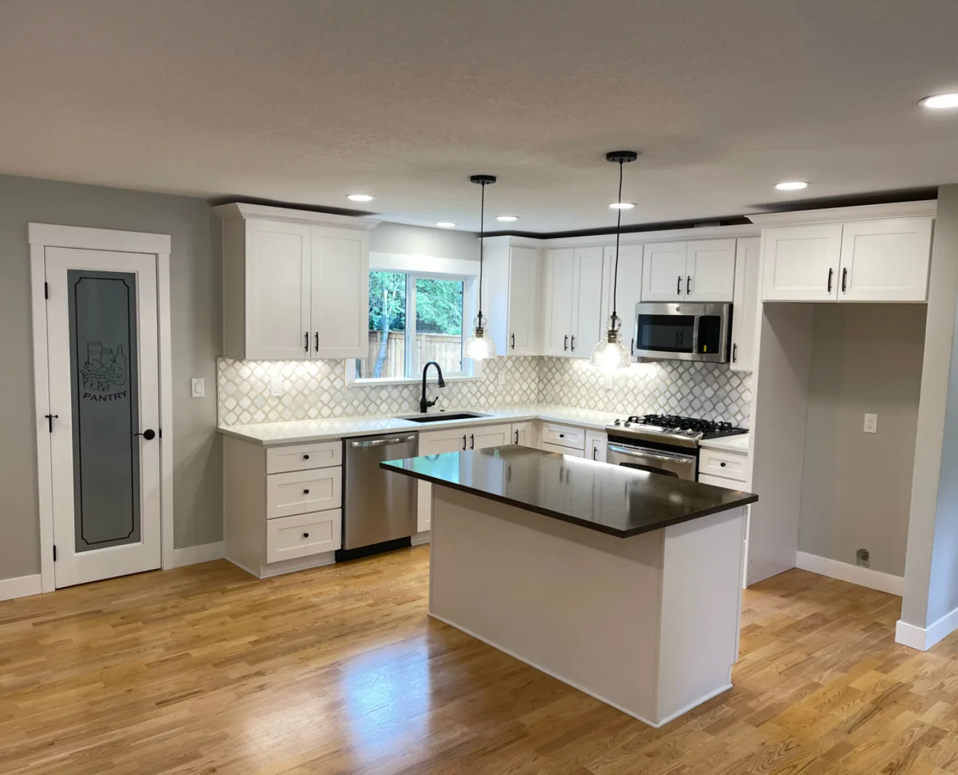 Portland kitchen renovation featuring custom quartz island and cabinetry craftsmanship by Pluum Construction
